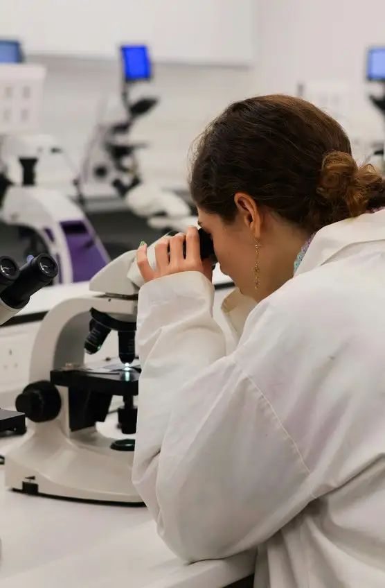 Researcher using a microscope at a dry laboratory bench