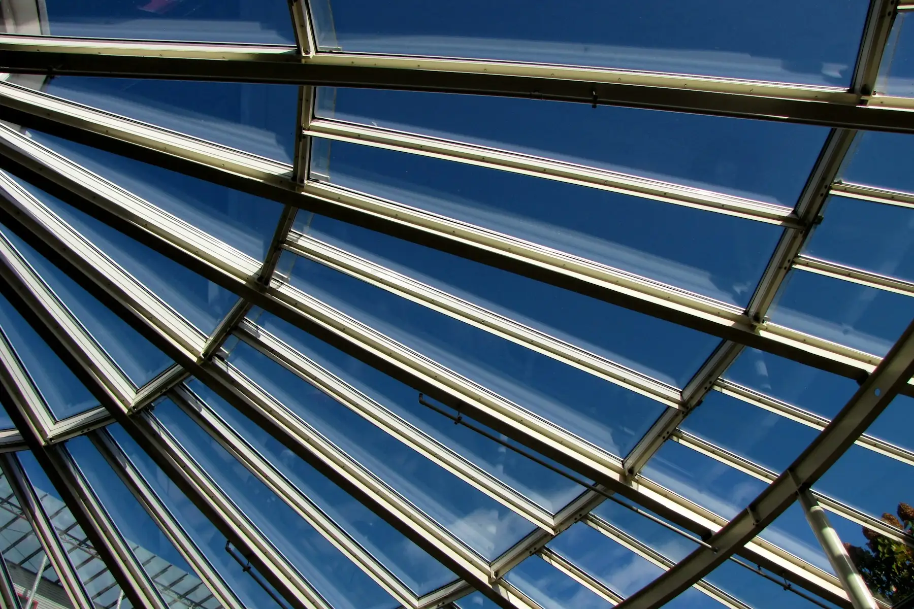 Overhead glass roof with metal framing against a blue sky